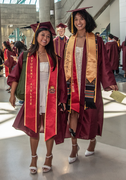 two young women in grad caps and gowns at convention center