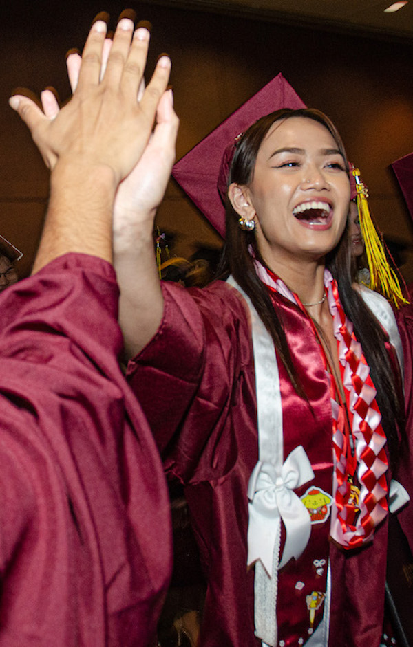 excited young woman in grad cap, giving high five