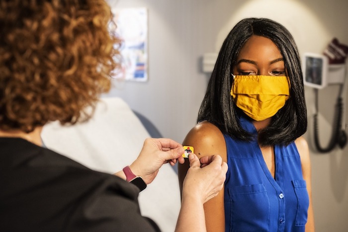 nurse applying bandaid on young woman's arm