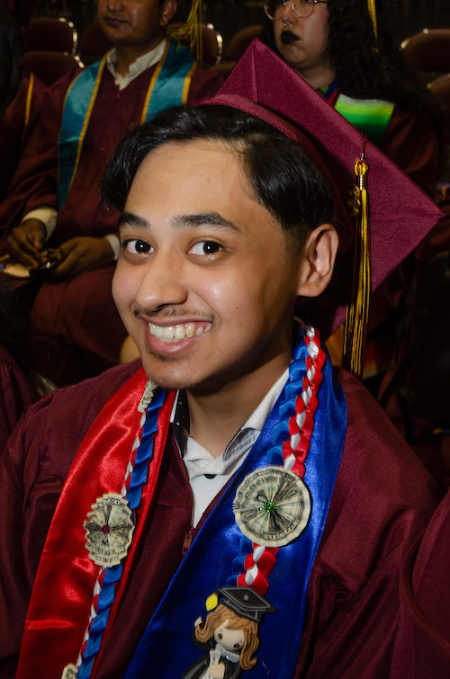 smiling young man in grad cap with necklace with dollars folded as flowers