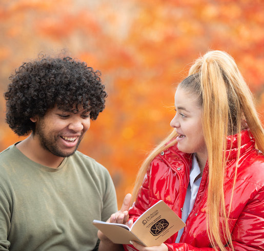 young woman showing booklet to smiling young man